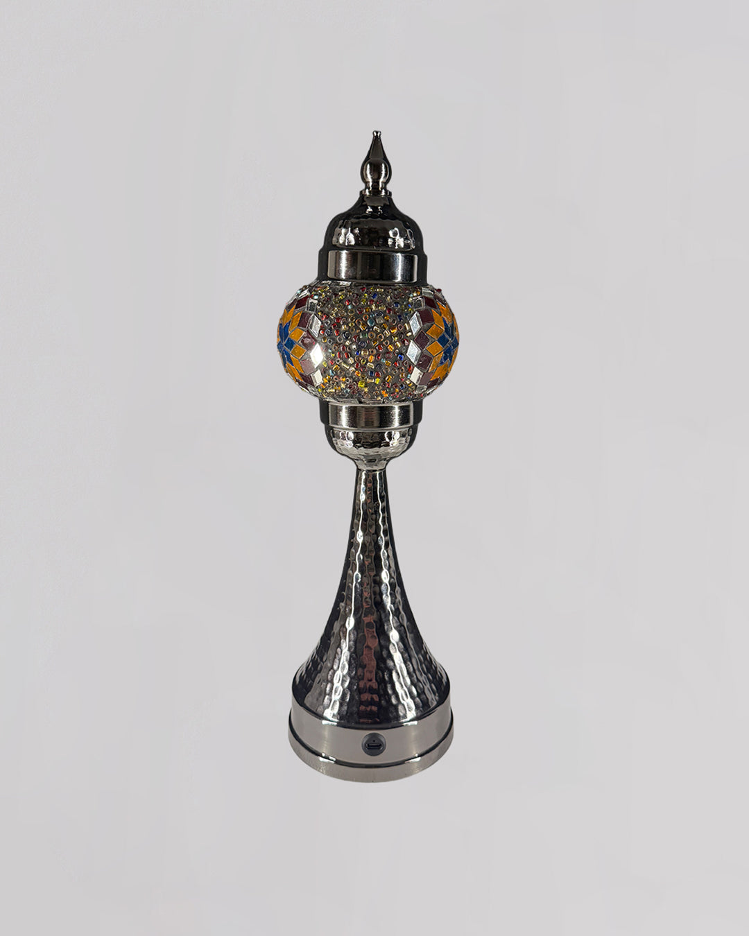 Decorative silver lamp with a colorful glass shade on a gray background