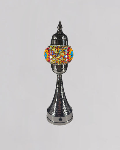 Decorative lamp with colorful glass shade and metallic base on a light gray background