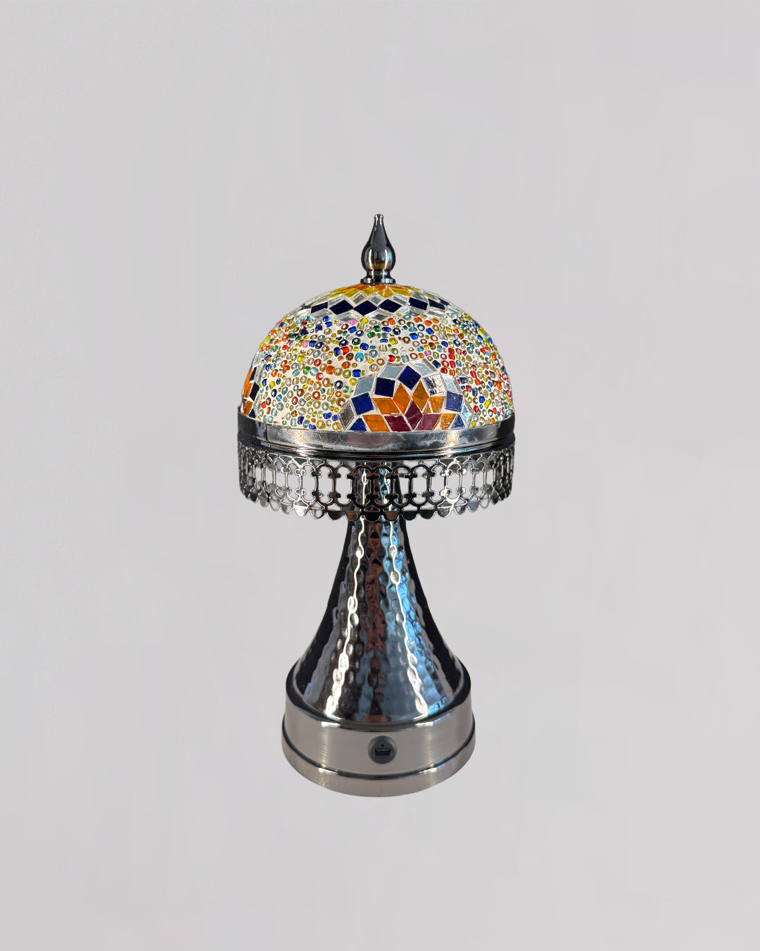 Decorative object with a colorful mosaic top and metallic base on a light gray background