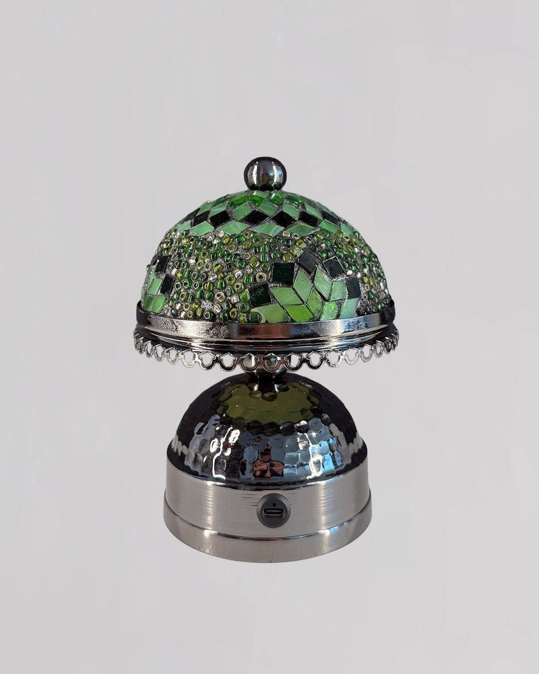 Decorative object with green mosaic top and metallic base on a light gray background