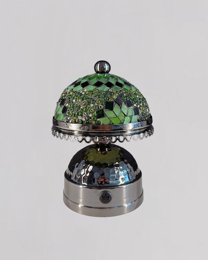 Decorative object with green mosaic top and metallic base on a light gray background