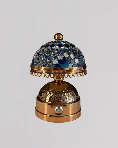 Decorative object with blue gemstones and gold accents on a gray background