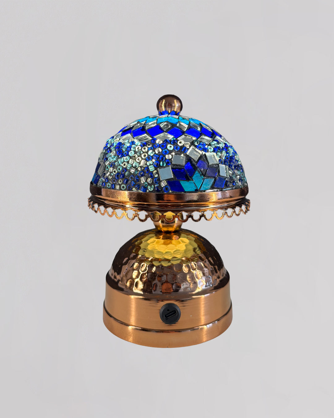 Decorative object with blue mosaic top and gold base on a light gray background