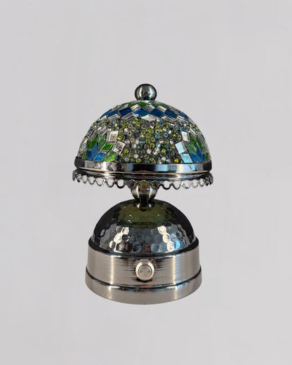 Decorative silver bell with mosaic top on a light gray background