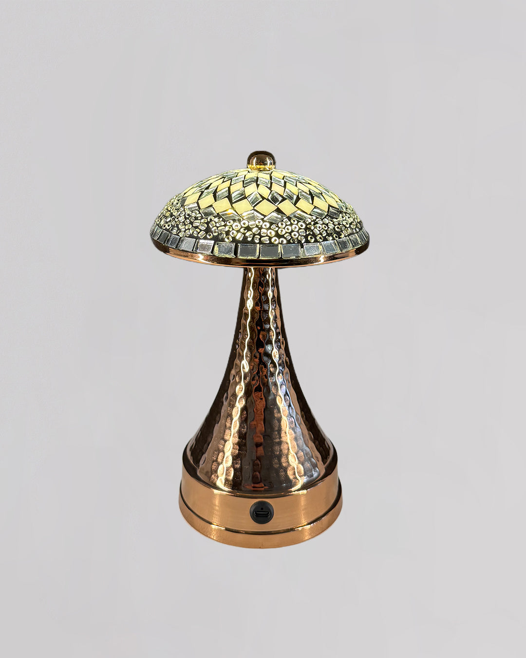Decorative lamp with a textured bronze base and mosaic glass shade on a light gray background