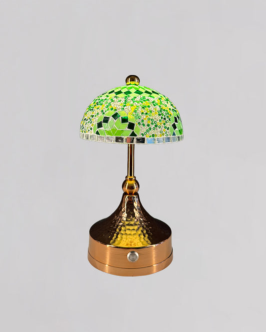 Decorative table lamp with a green mosaic shade on a gray background