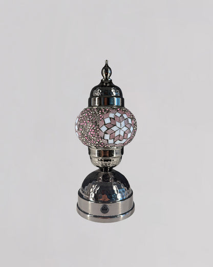 Decorative lamp with a silver base and pink mosaic shade on a white background
