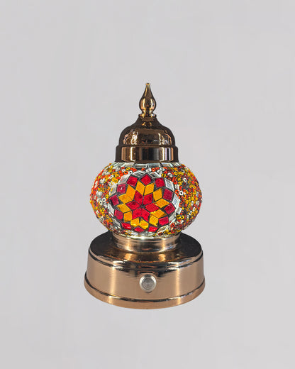 Decorative mosaic lamp with orange and red glass creating rich and warm light.
