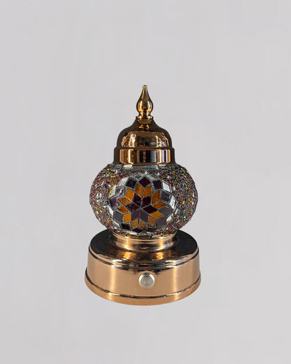 Decorative mosaic lamp with orange and red glass creating rich and warm light.