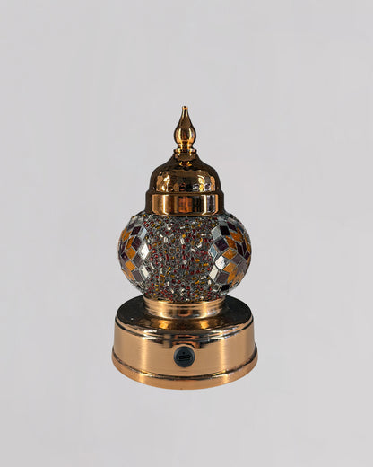 Decorative mosaic lamp with orange and red glass creating rich and warm light.